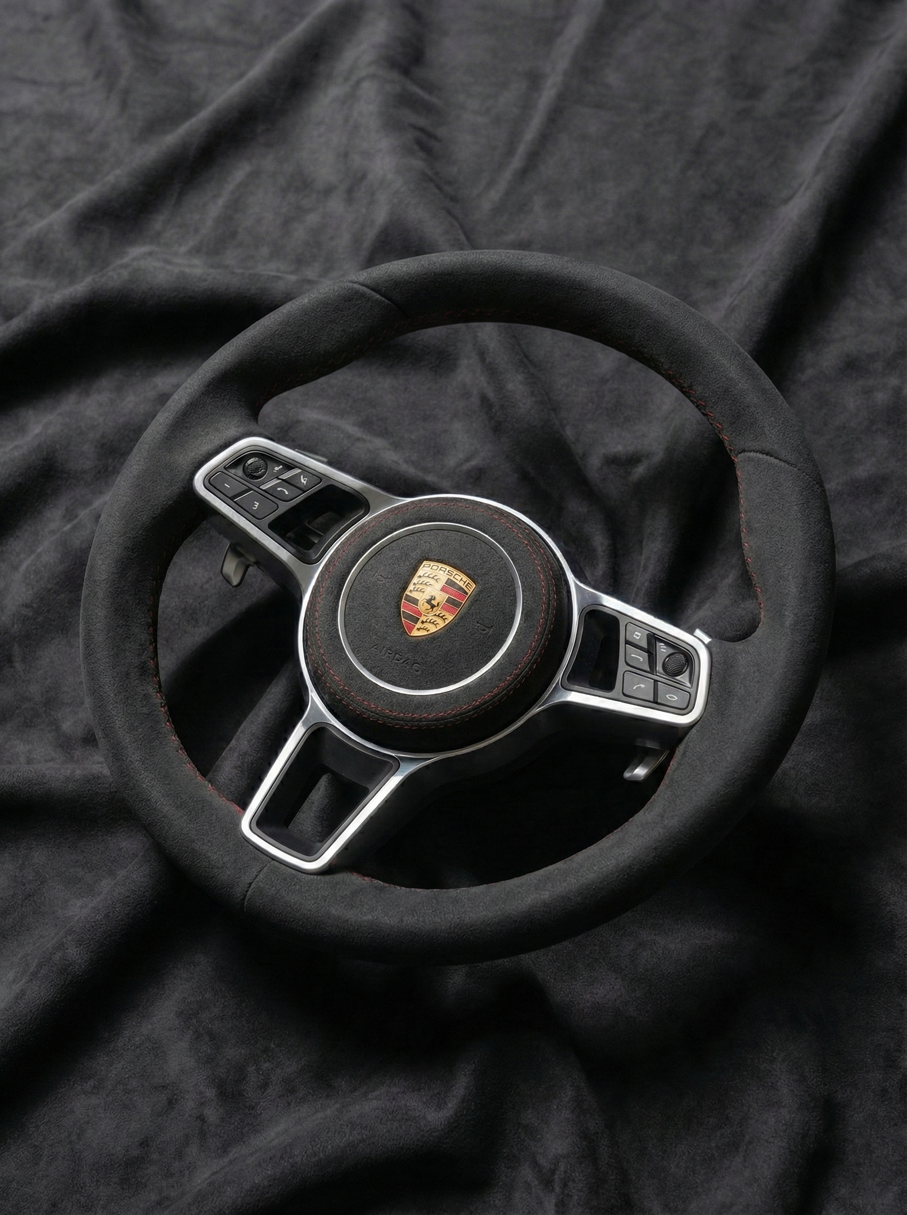 Steering wheel with Porsche logo on a dark fabric background