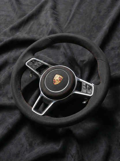 Steering wheel with Porsche logo on a dark fabric background