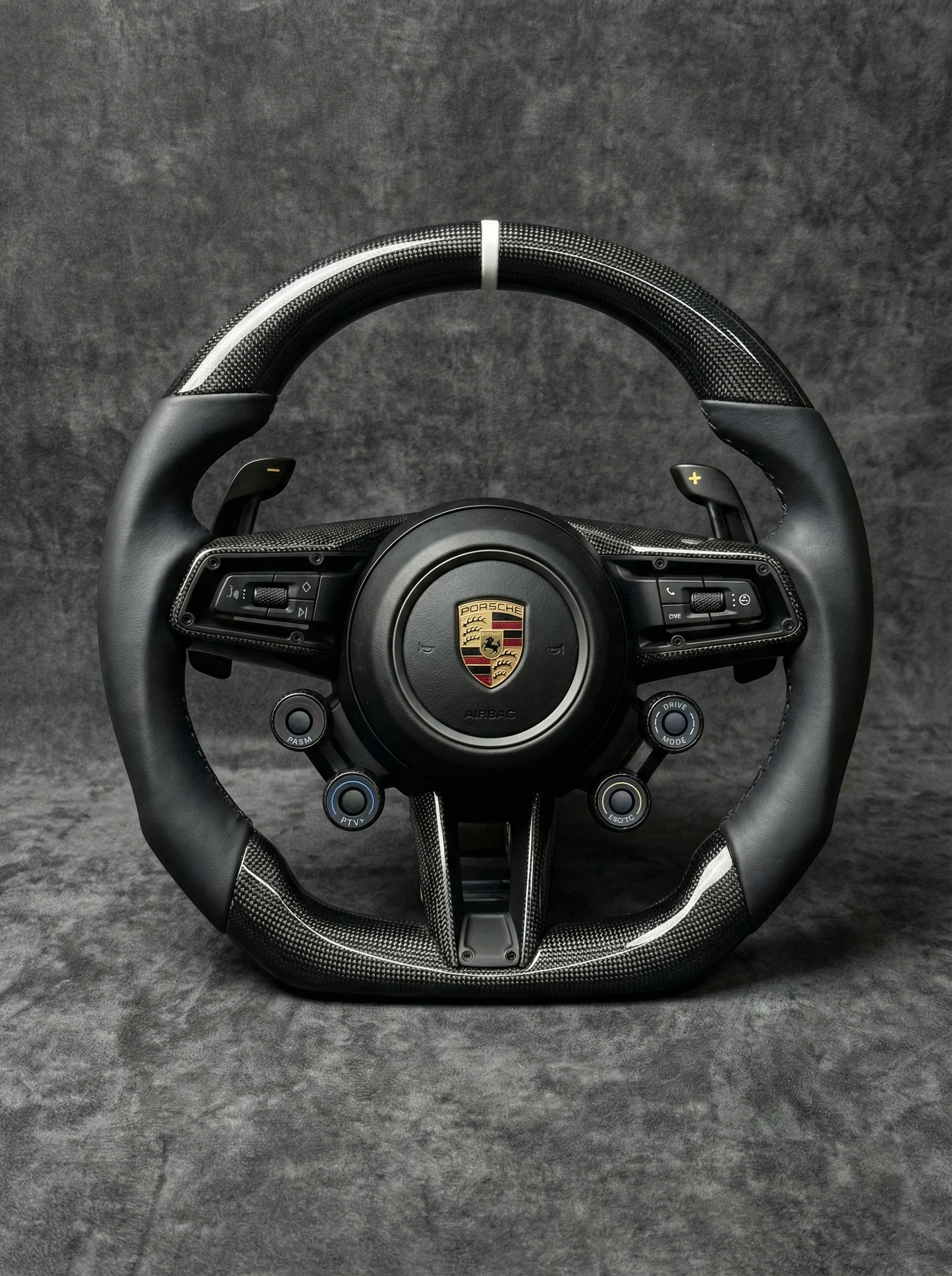 Black steering wheel with Porsche logo on a gray background