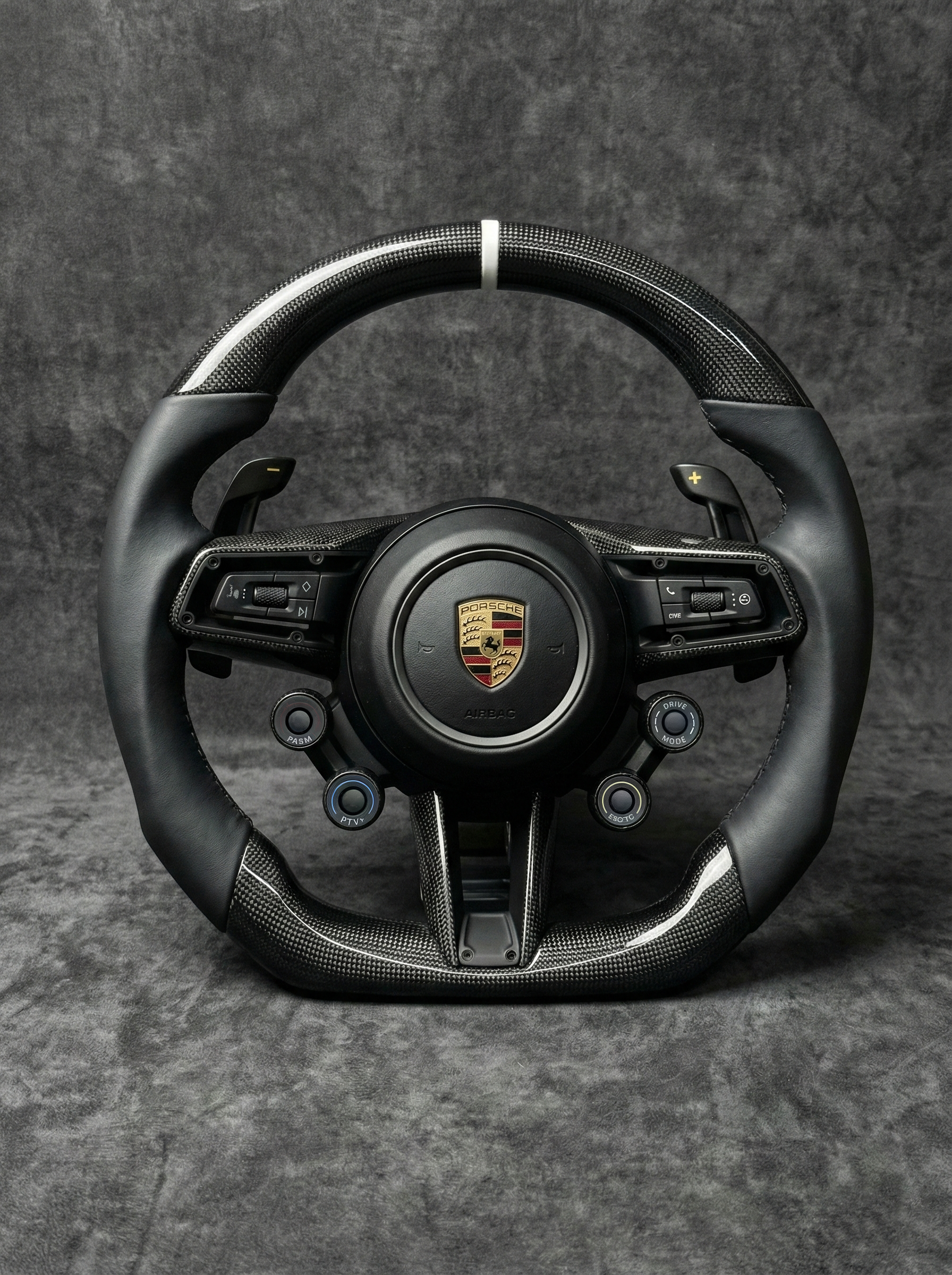 Black steering wheel with Porsche logo on a gray background
