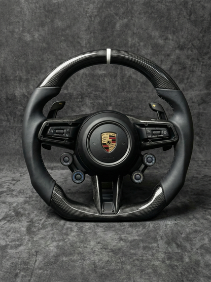 Black steering wheel with Porsche logo on a gray background