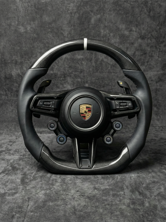 Black steering wheel with Porsche logo on a gray background