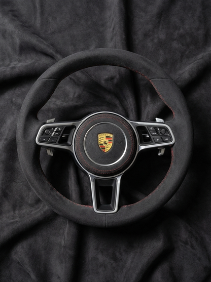 Steering wheel with Porsche logo on a dark fabric background