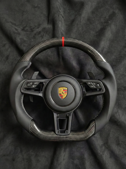 Steering wheel with Porsche logo on a dark background