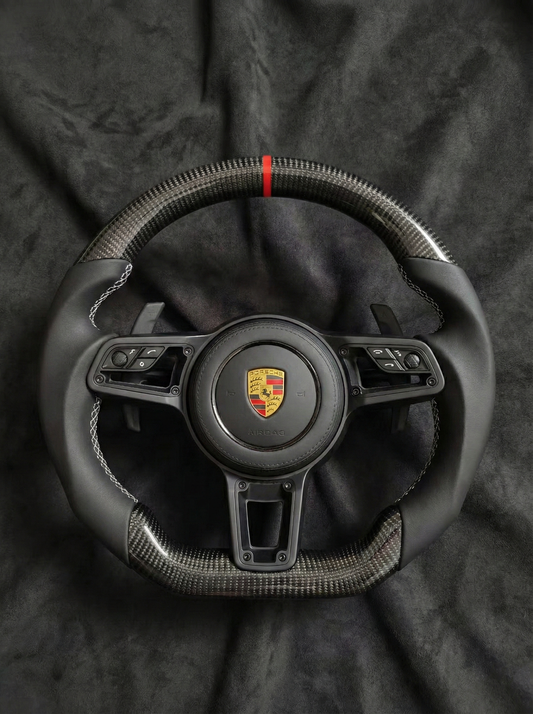 Steering wheel with Porsche logo on a dark background
