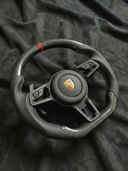 Black steering wheel with Porsche logo on a dark fabric background