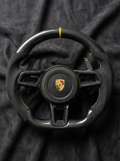Black Porsche steering wheel with logo on a dark fabric background