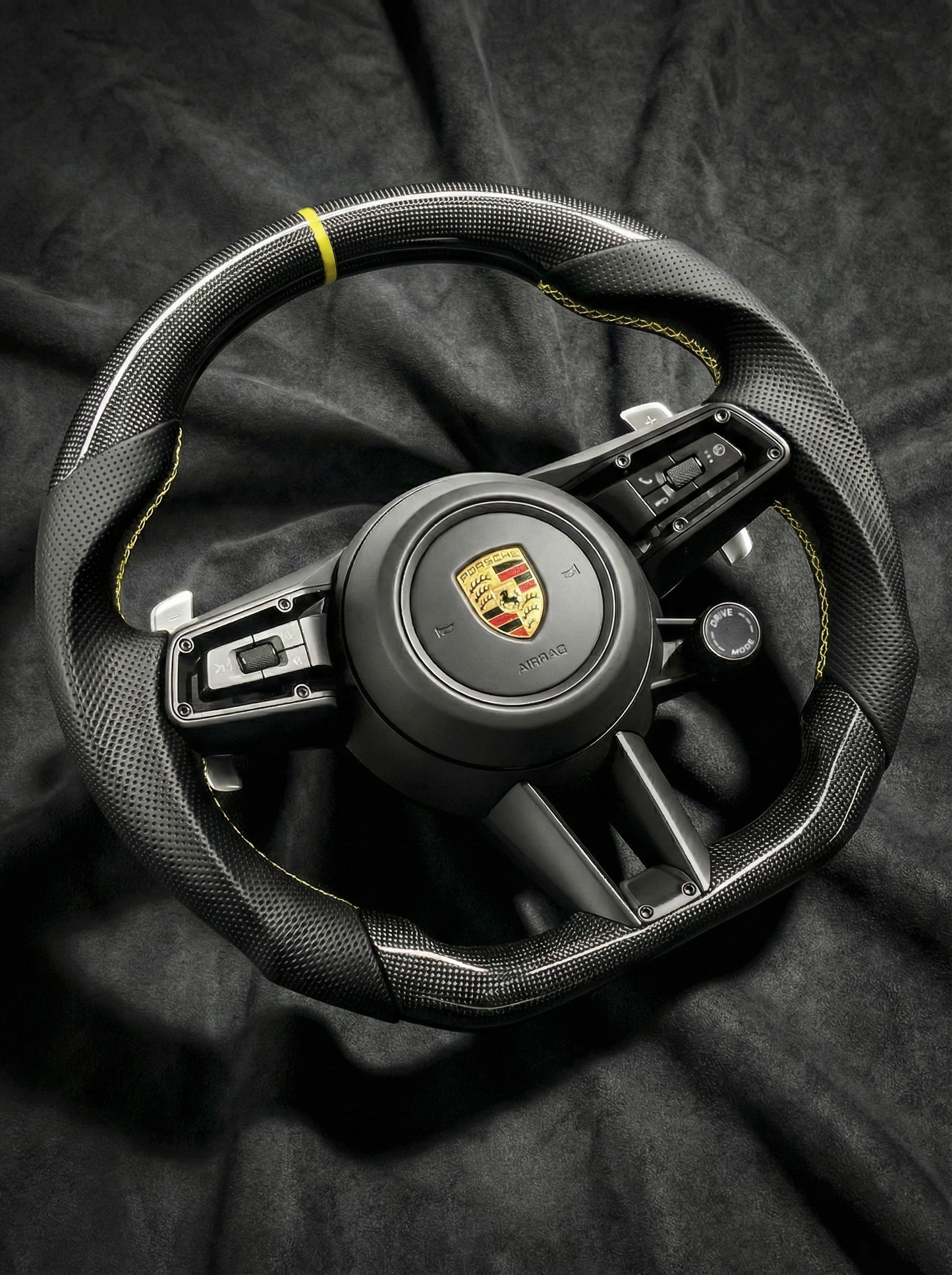 Steering wheel with Porsche logo on a dark background