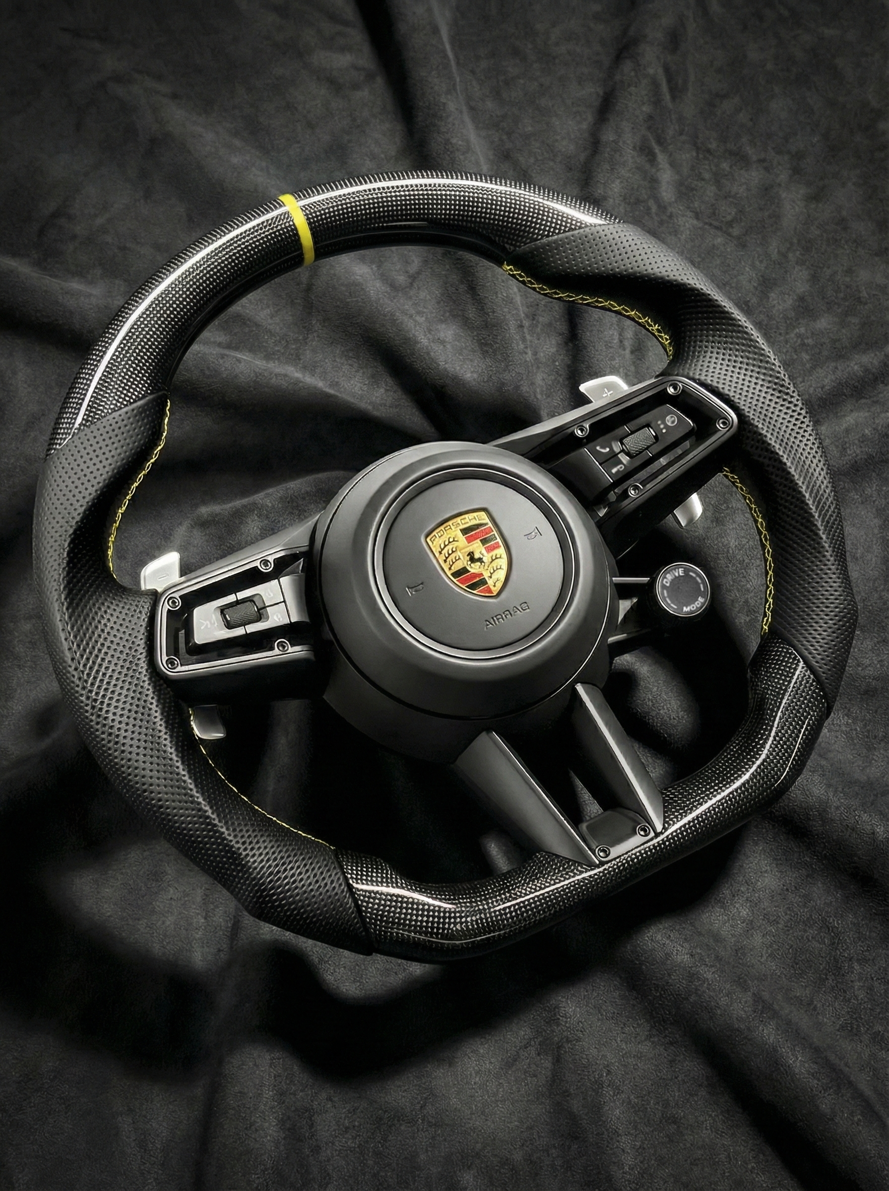 Steering wheel with Porsche logo on a dark background