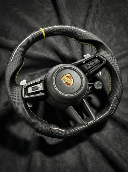 Steering wheel with Porsche logo on a dark background
