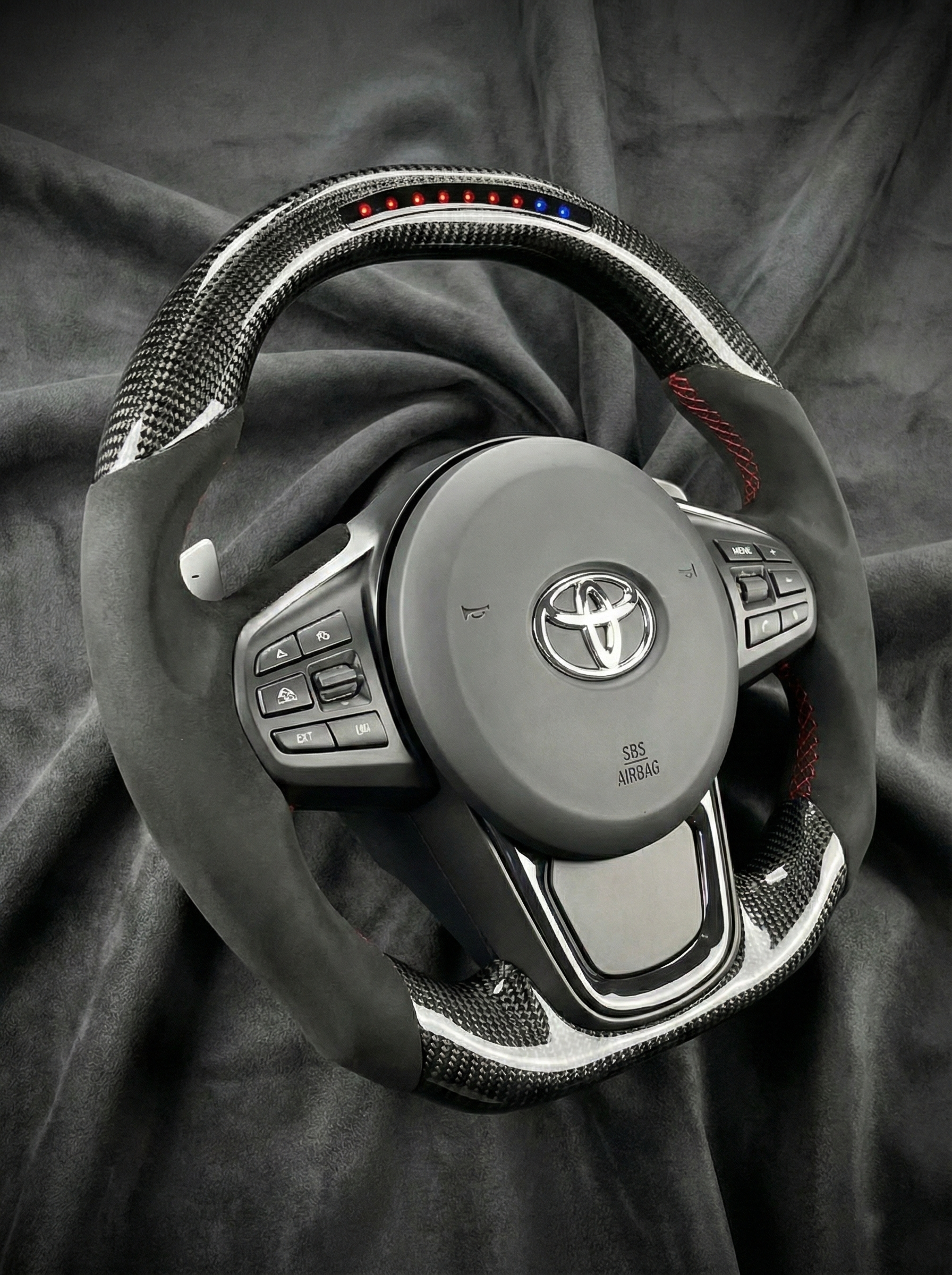 Car steering wheel with Toyota logo on a dark fabric background