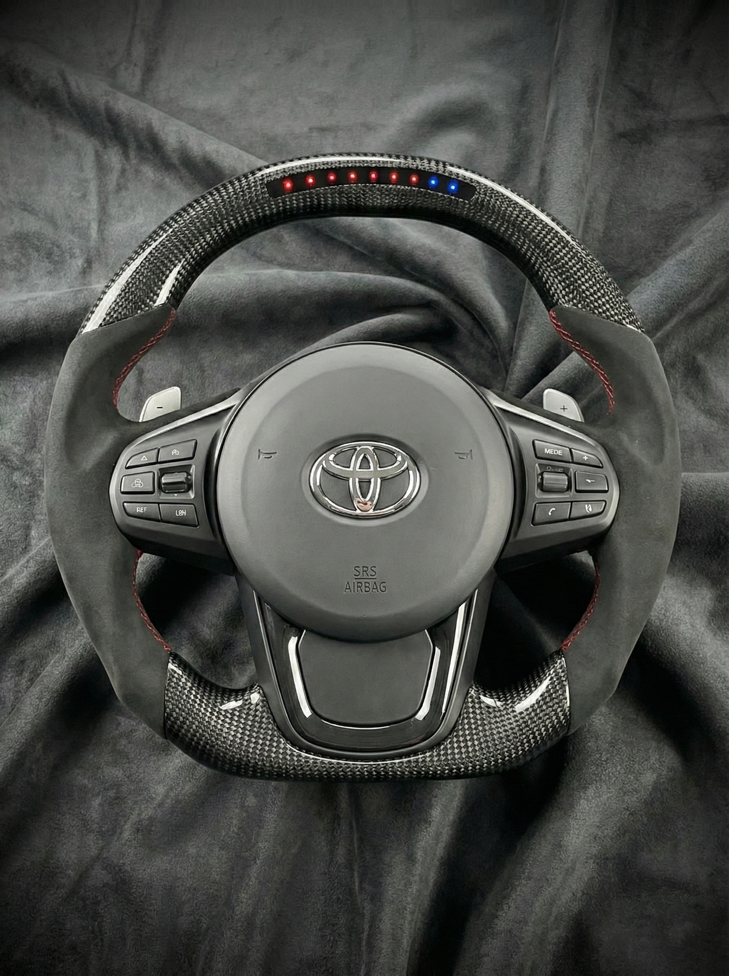 Car steering wheel with Toyota logo on a dark fabric background