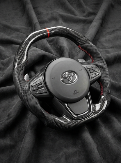 Car steering wheel with Toyota logo on a dark fabric background