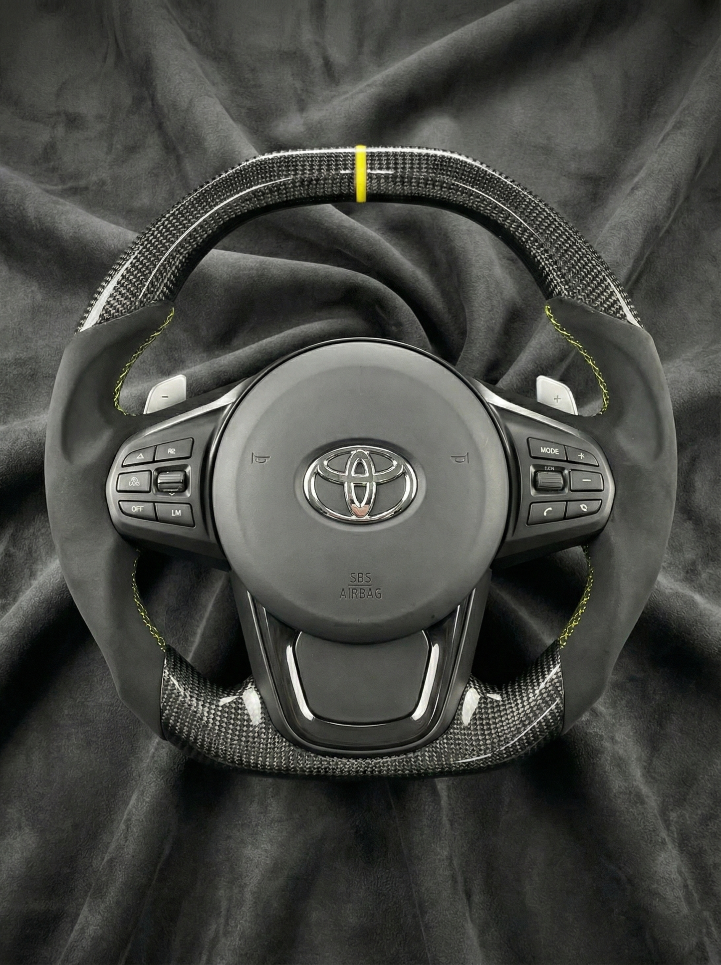 Car steering wheel with Toyota logo on a dark fabric background