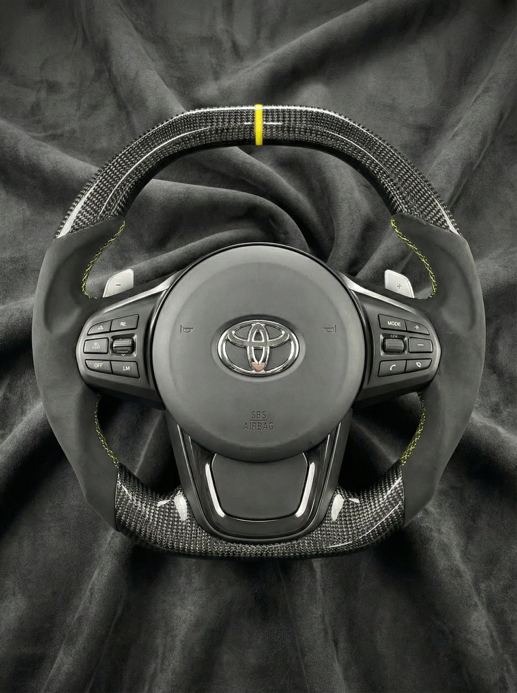 Car steering wheel with Toyota logo on a dark fabric background