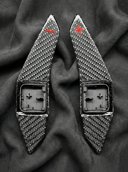 Two carbon fiber patterned objects on a dark fabric background